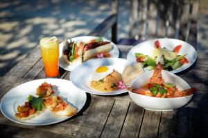 quatro pratos de comida numa mesa de madeira com sumo de laranja em Blue Marlin Dive Resort Trawangan em Gili Trawangan