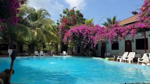 a pool with blue water and purple flowers at Oasis2 Phuket Airport Glamping in Phuket