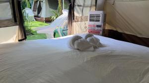 a white towel laying on a bed in a tent at Oasis2 Phuket Airport Glamping in Phuket