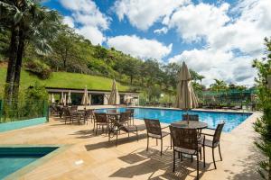 a patio with tables and chairs next to a swimming pool at Loft no Granja Brasil Resort, Itaipava centro, Estrutura Completa in Araras Petropolis