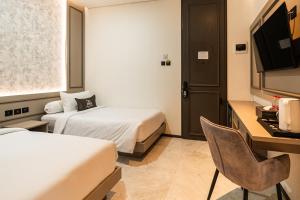 a hotel room with two beds and a desk at Casa De Zea by AKA in Yogyakarta