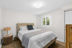 a white bedroom with a bed and a window at Blue View Gerringong in Gerringong