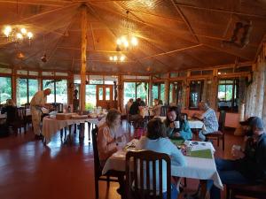 a group of people sitting at tables in a restaurant at Kluges Guest Farm in Kibale
