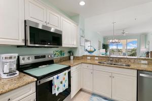 a kitchen with white cabinets and a black stove top oven at Spacious Condo - 2 King Suites - Close to Beaches in Marco Island