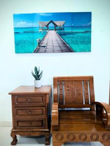 a boardwalk in the ocean with a table and a plant at Mama Nusantara Hotel in Jertih