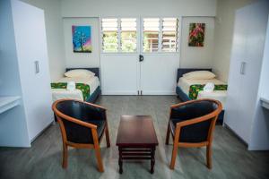 a room with two beds and a table and two chairs at Yatulau Hotel and Conference in Suva +14 photos