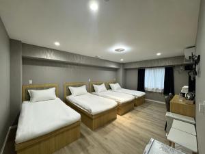 a room with three beds and a desk at Ruka Hotel Tennoji in Osaka