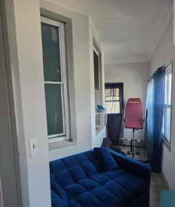 a living room with a blue couch and two windows at Grove 4- Queen bed with Private bathroom in Irvington