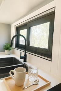 a kitchen sink with a cup and a glass on a cutting board at Tiny Home in Casula Station