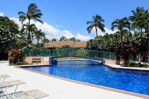 a swimming pool with a bridge and palm trees at Unique Artist Home Steps from the Ocean in Kihei