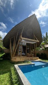 a house with a large roof next to a swimming pool at Bamboo Garden Villa Sidemen - Private Pool & Nature View in Selat