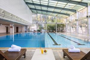 a large swimming pool with two chairs in a building at Novotel Changshu Yushan in Changshu