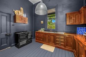 a kitchen with wooden cabinets and a sink and a stove at Glenrock Homestead in Bulga +14 photos
