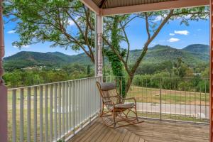 a rocking chair on a porch with a view of mountains at Glenrock Homestead in Bulga