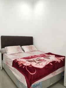 ein Bett mit einer roten Decke darauf in der Unterkunft Mesirom B&B in Dili