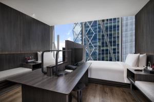 a hotel room with a bed and a desk with a monitor at Discovery SCBD Jakarta in Jakarta