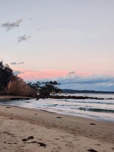 a beach with a sunset and the ocean at Saltwater Daze - Hosted in Sunshine Bay