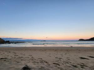a sandy beach with a sunset in the background at Saltwater Daze - Hosted in Sunshine Bay