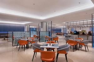 a restaurant with tables and chairs in a room at Novotel Changshu Yushan in Changshu
