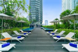 a row of chairs and umbrellas next to a pool at Discovery SCBD Jakarta in Jakarta