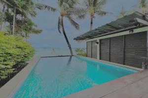 a swimming pool in front of a house with palm trees at The Shore Samui in Bangrak Beach