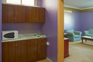 利雅德的住宿－Al Farhan Hotel Suites Al Aqiq，厨房设有紫色墙壁和台面上的微波炉