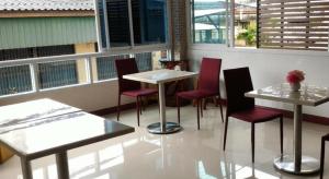 a restaurant with tables and red chairs and windows at V-House Hotel in Trang +34 photos