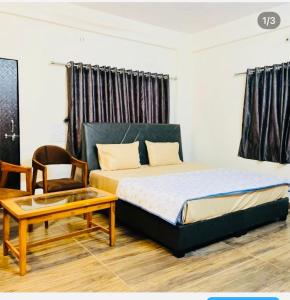 a bedroom with a bed and a table and a chair at Raj Hotel in Talala