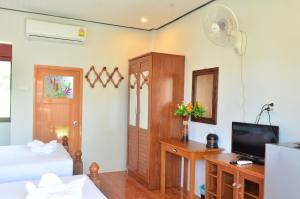 a bedroom with a bed and a tv and a desk at Phongpipat Lanta Mansion in Ko Lanta