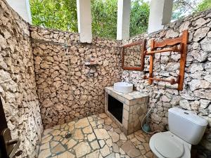 a stone bathroom with a toilet and a sink at Mangga Lodge in Bira +62 photos