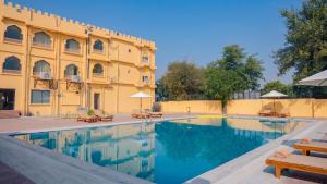 a swimming pool in front of a building at Haut Monde Rajputana Palace in Behror