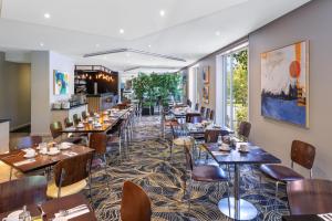 a restaurant with tables and chairs in a room at BEST WESTERN PLUS Travel Inn in Melbourne