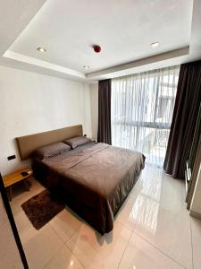 a bedroom with a large bed and a large window at Apartment Serenity Wongamat in North Pattaya