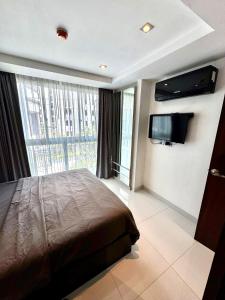 a bedroom with a bed and a flat screen tv at Apartment Serenity Wongamat in North Pattaya