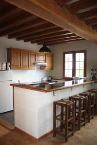 una cucina con mobili in legno e un bancone con sgabelli di Le Haut-Val Résidences a Bellême