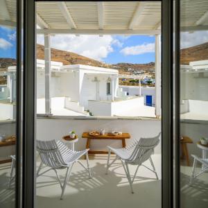 two chairs and a table on a balcony with a view at ALASI Tinos Jacuzzi Hotel in Agios Ioannis