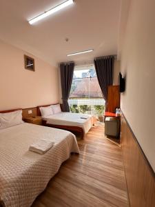 a hotel room with two beds and a window at Hoa Cattleya Hotel in Da Lat