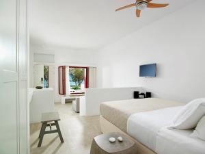 a white bedroom with a bed and a tv at Unique Milos Suites in Pollonia
