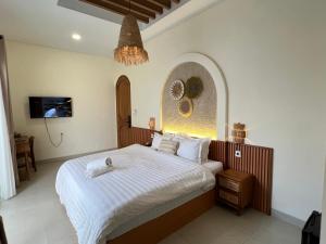 a bedroom with a bed with white sheets and a chandelier at Numar Villas Yogyakarta in Seturan +42 photos