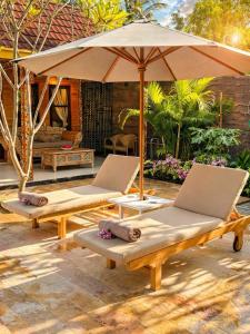 two lounge chairs and an umbrella on a patio at Namali Private Villa in Gili Trawangan