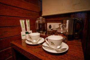 two cups and saucers sitting on a wooden counter at Stanmore Garden Bungalow in Vālpārai +4 photos