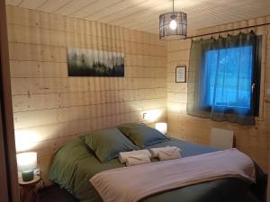 a bedroom with a bed with two pillows and a window at Le Chalet de l'Ancerf in Faucompierre