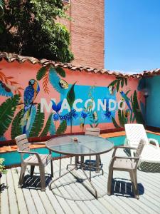 Ein Tisch und Stühle vor einer Wand mit einem Wandgemälde in der Unterkunft Macondo Hostel in San Gil