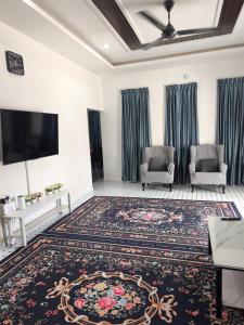 a living room with two chairs and a flat screen tv at Dsurau Homestay in Kota Bharu