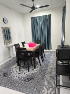 a dining room with a table and chairs on a rug at Dsurau Homestay in Kota Bharu