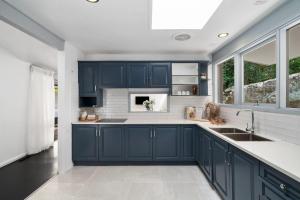 a kitchen with navy blue cabinets and a sink at Tranquil bush resort house - pool & fire pit in Pymble