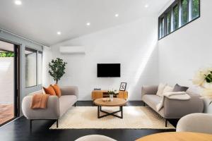 a living room with two couches and a tv at Tranquil bush resort house - pool & fire pit in Pymble
