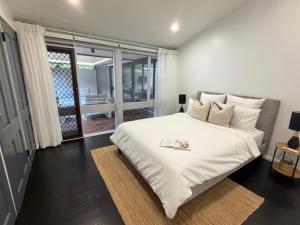 a bedroom with a large white bed and a balcony at Tranquil bush resort house - pool & fire pit in Pymble +25 photos