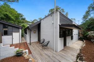 a house with a wooden deck with a chair on it at Tranquil bush resort house - pool & fire pit in Pymble