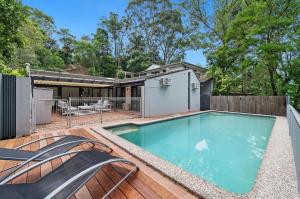 a swimming pool on a deck with a house at Tranquil bush resort house - pool & fire pit in Pymble